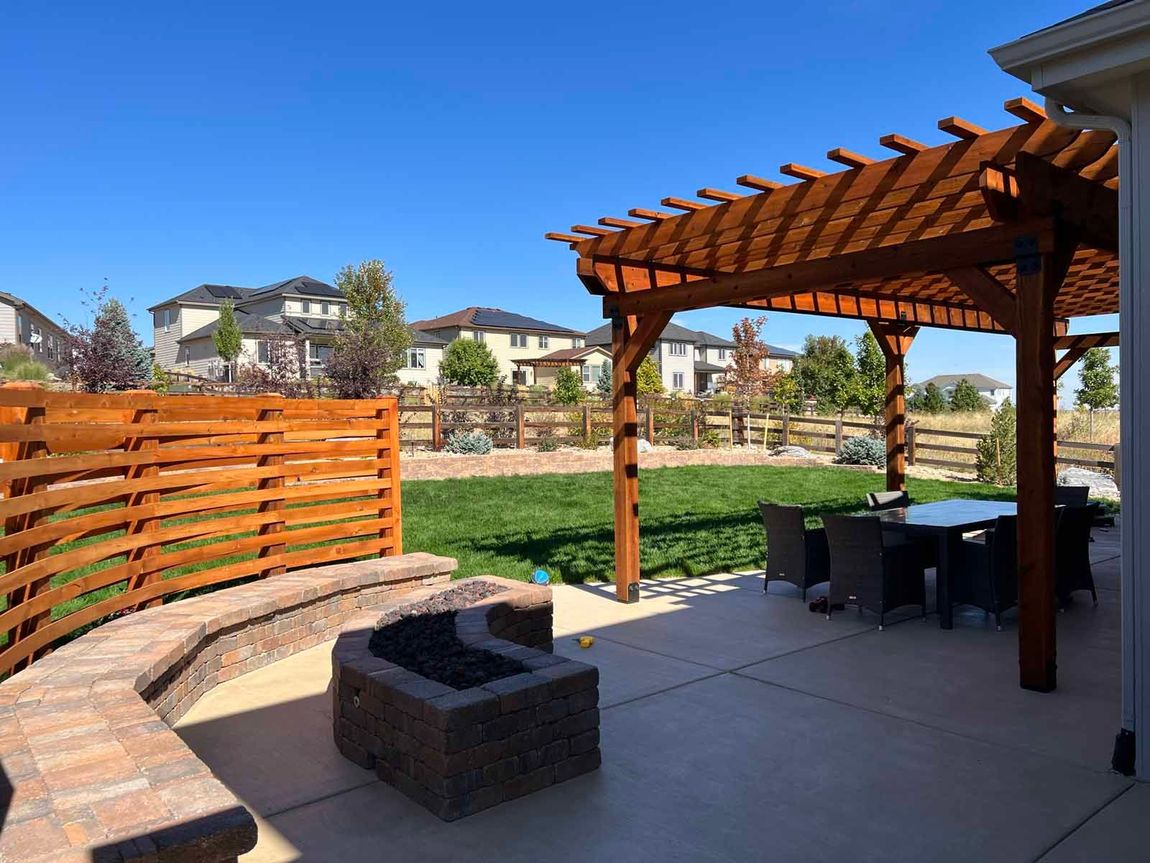 A patio with a pergola and a fire pit