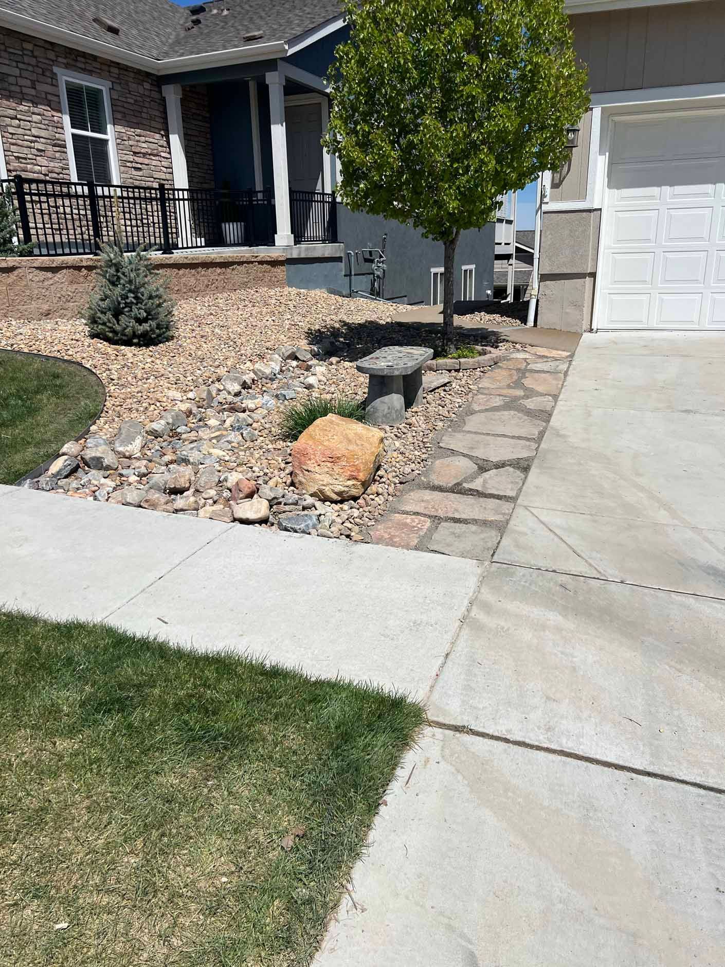 A house with a driveway and a tree in front of it.